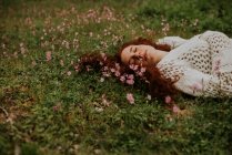 Dreamy girl lying on ground with blooming pink petals — Stock Photo