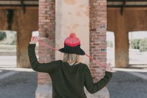 Девушка в вязаной шляпе держалась за руки с подтяжками в сторону — стоковое фото