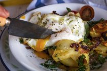 Обрізати руку ножем нарізаючи смажене яйце і картоплю — стокове фото