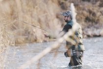 Seitenansicht eines Mannes, der mit im Wasser stehender Rute fischt. — Stockfoto