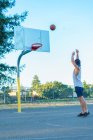 Giovane uomo che lancia palla da basket — Foto stock