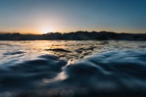 Água azul da onda do mar no fundo do pôr do sol . — Fotografia de Stock