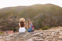 Meninas sentadas juntas na borda da montanha — Fotografia de Stock