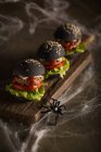 Fila de hambúrgueres halloween em tábua de madeira — Fotografia de Stock