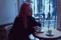 Schläfrige, erschöpfte Frau sitzt im Café und trinkt Kaffee. — Stockfoto