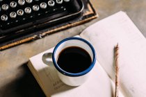 Tasse mit Kaffee auf aufgeschlagenem Buch — Stockfoto