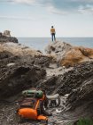 Вид ззаду мандрівника, що стоїть на скелястих скелях і захоплюючий океанський пейзаж — стокове фото