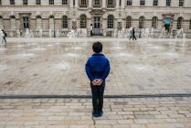 Лондон, Великобританія - 4 травня 2017: Назад подання маленький хлопчик стоїть перед площі з фонтанами, бризки води. — стокове фото