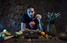 Мужчина регулирует клубнику на стакане для коктейля — стоковое фото