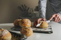 Женские руки режут свежеиспеченный хлеб — стоковое фото