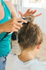 Cropmother cutting son's hair with electric machine — Stock Photo