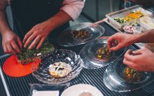 Руки на полях, собирающие ингредиенты для посуды на кухне ресторана — стоковое фото