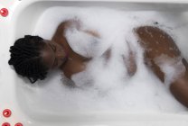 Черная девушка принимает ванну с пеной — стоковое фото