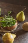 Close up view of bowl with fresh spinach leaves on table with pear and kiwi — Stock Photo