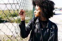 Woman holding fence and looking aside — Stock Photo