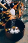 Spoon adding sugar to plums in saucepot — Stock Photo