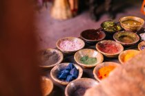 Pequeños cuencos de cerámica con polvo brillante de diferentes colores en la mesa . - foto de stock