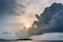 Nube de tormenta esponjosa en el cielo colorido sobre la superficie del mar . - foto de stock