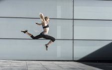 Mujer deportiva en salto de gran alcance - foto de stock