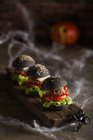 Fila de hambúrgueres halloween em tábua de madeira — Fotografia de Stock