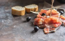 Cured ham with bread and olives — Stock Photo