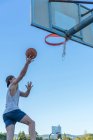 Hombre lanzando pelota en el anillo de baloncesto - foto de stock