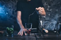 Mani maschili che mettono gli igridienti nel bicchiere da cocktail — Foto stock