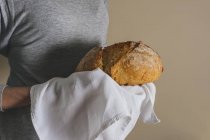 Mani femminili che tengono un pane rustico — Foto stock