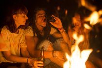 Friends drinking beer at bonfire — Stock Photo