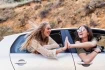 Amigos dando alta cinco enquanto montando carro — Fotografia de Stock