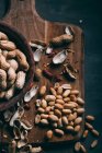 Vista da vicino di arachidi in ciotola di legno sul tagliere su sfondo scuro — Foto stock