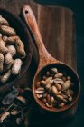 Vista de perto de amendoins descascados em colher de madeira a bordo — Fotografia de Stock