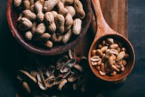 Erdnüsse in Holzschaufel und Schüssel auf Schneidebrett — Stockfoto