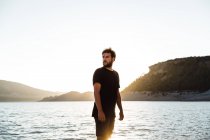 Homem posando na praia e olhando para longe — Fotografia de Stock