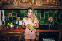 Ritratto di ragazza allegra che tiene banane in cucina — Foto stock