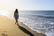 Visão traseira da mulher andando na praia — Fotografia de Stock