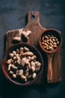 Top view of various peanuts in wooden bowl and scoop on cutting board — Stock Photo