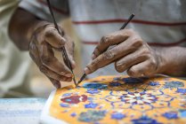 Close-up hand of person drawing on traditional Indian mandala — Stock Photo