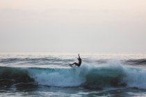 Vista lateral del surfista cabalgando sobre la ola - foto de stock