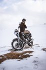 Man wearing motorcycle helmet in snowy highlands — Stock Photo