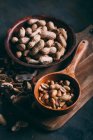 Натюрморт из арахиса в деревянной чаше и совок на доске — стоковое фото