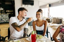 Улыбающийся мужчина кормит улыбчивую женщину картошкой фри — стоковое фото