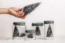 Récolte de main féminine tenant arbre de Noël décoratif sur des pots avec des décorations de Noël — Photo de stock