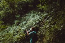 Вид ззаду людини, що йде в лісі і вказує пальцем убік — стокове фото