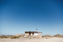 Homem em posar perto de pequena cabana no deserto no dia ensolarado . — Fotografia de Stock