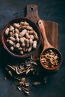 Top view of peanuts in wooden bowl and scoop board on dark background — Stock Photo