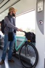 Hombre barbudo cabalgando en tren con bicicleta y escuchando música - foto de stock