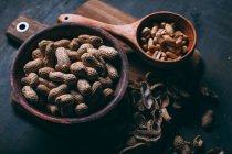 Close up view of shelled peanuts in wooden bowls cutting board — Stock Photo