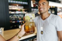 Erntehelferin prostet Mann an Bar mit Cocktail zu — Stockfoto