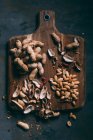 Top view of peeled and shelled peanuts on wooden board with peels — Stock Photo